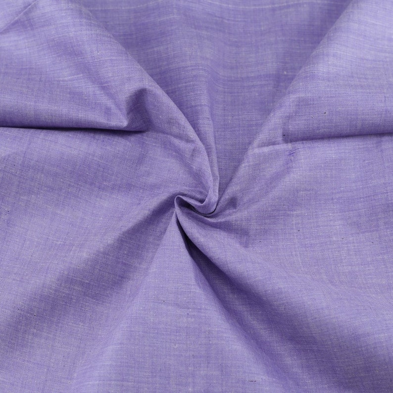 Op de afbeelding: Een close-up van een zachte, lichtpaarse stof met een subtiele textuur. De stof is gevouwen en gekreukt, wat de drape en flexibiliteit laat zien.