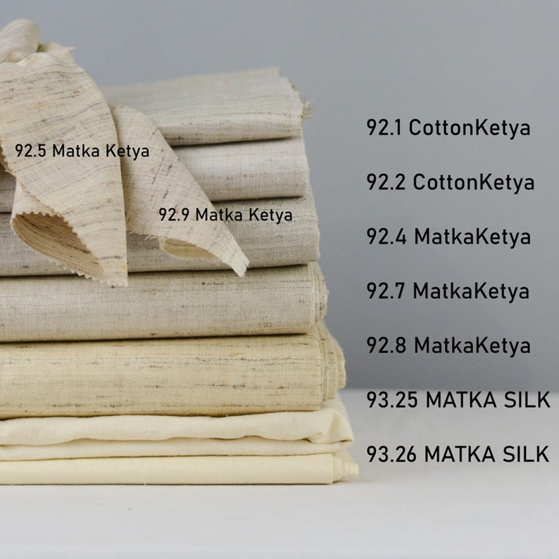May include: A stack of eight different fabric swatches in various shades of beige and white. The swatches are labeled with numbers and fabric types, including "Matka Ketya" and "MATKA SILK".