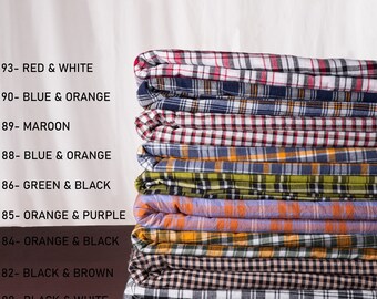 May include: A stack of eight plaid fabrics in various colors, including red, white, blue, orange, green, black, maroon, and purple. Each fabric has a different color combination and pattern. The fabrics are labeled with numbers and color combinations.