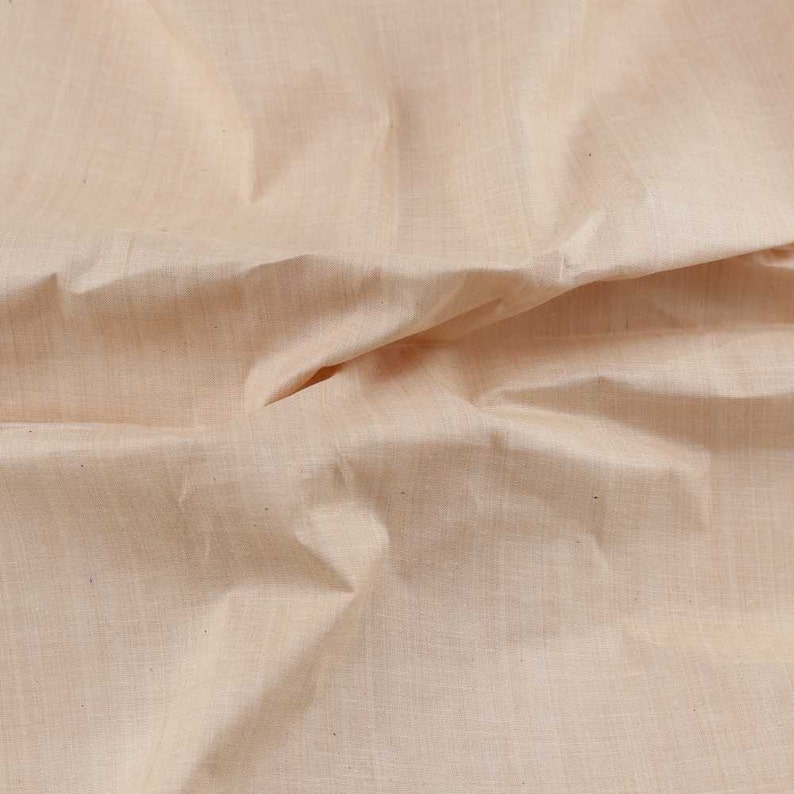 Pu&ograve; includere: Un primo piano di un tessuto liscio color beige chiaro con una texture sottile. Il tessuto &egrave; piegato e drappeggiato, mostrando la sua natura morbida e fluida.