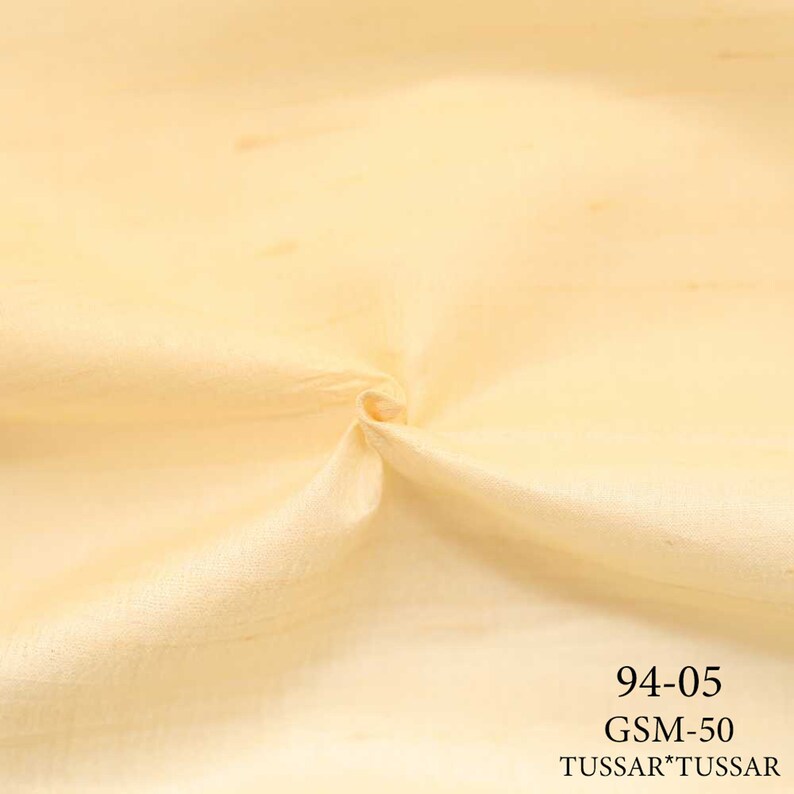 May include: A close-up of a pale yellow fabric with a smooth texture. The fabric is folded and has a slight sheen. The text "94-05 GSM-50 TUSSAR*TUSSAR" is printed in black at the bottom of the image.