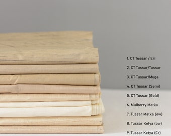 May include: A stack of nine different types of fabric swatches in various shades of beige and cream. The fabric swatches are labeled with their names, including "CT Tussar / Eri", "CT Tussar/Tussar", "CT Tussar/Muga", "CT Tussar (Semi)", "CT Tussar (Gold)", "Mulberry Matka", "Tussar Matka (ow)", "Tussar Ketya (ow)", and "Tussar Ketya (Cr)".