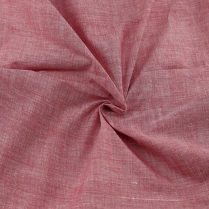 Op de afbeelding: Close-up van een zachte, rode stof met een subtiel textuurpatroon. De stof is gevouwen en gedrapeerd, waardoor de drape en textuur worden getoond.