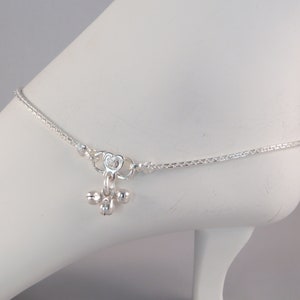 May include: Silver anklet with a heart charm and dangling bells.