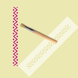 Peut inclure: Un pochoir blanc avec un motif en zigzag et des points. Un petit pinceau est posé sur le pochoir.
