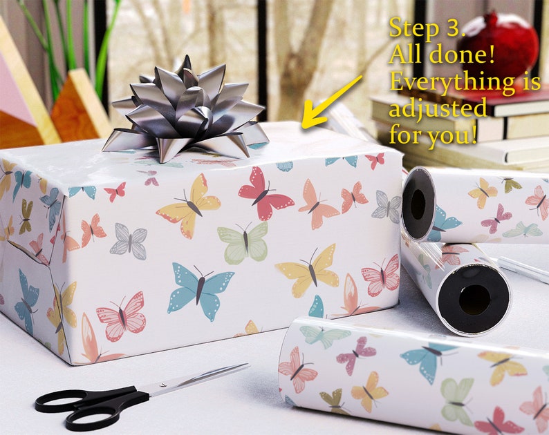 May include: A wrapped gift box with butterfly-patterned paper and a silver bow. Rolls of matching wrapping paper and scissors are nearby. Text on the image reads: "Step 3. All done! Everything is adjusted for you!"