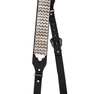 May include: Black leather guitar strap with a silver scale pattern and a silver buckle.
