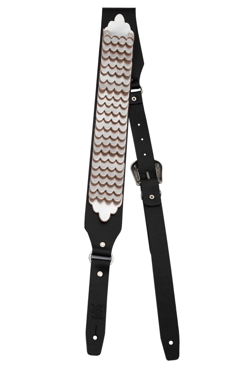 May include: Black leather guitar strap with a silver scale pattern and a silver buckle.