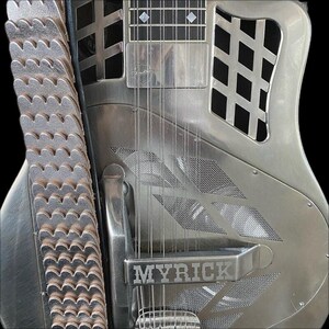 May include: A silver-coloured electric guitar with a metal body and a  "MYRICK" inscription on the front. The guitar has a  grid pattern on the body and a  metal strap.