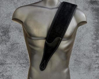 May include: Black leather guitar strap with white stitching and a small round logo. The strap is shown on a mannequin.