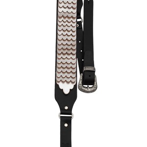 May include: Black leather guitar strap with a silver scale pattern and a silver buckle.