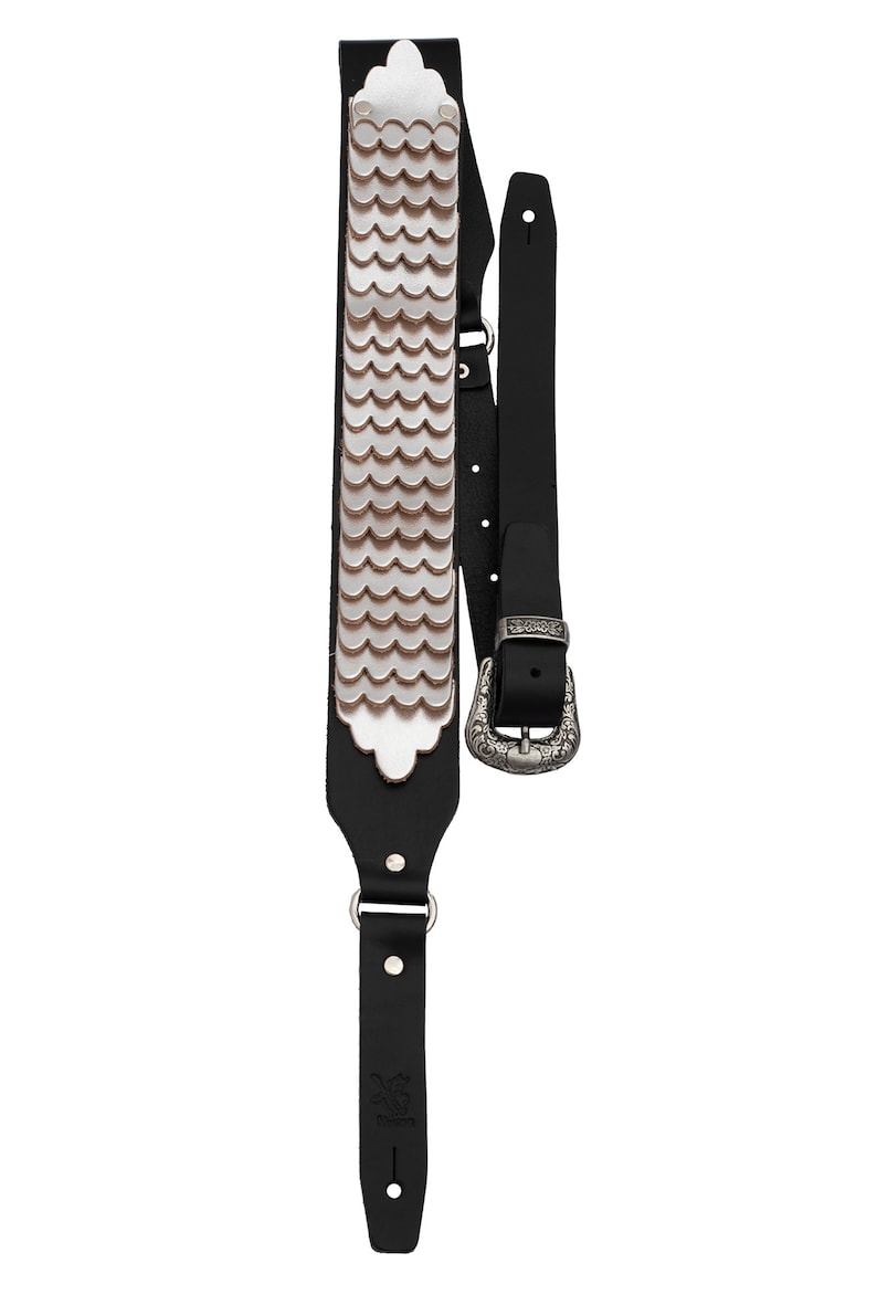 May include: Black leather guitar strap with a silver scale pattern and a silver buckle.