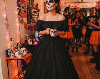 May include: A floor-length black off-the-shoulder dress with a ruffled hem and short sleeves. The garment features a fitted bodice and a full, voluminous skirt. The fabric appears to be a solid, opaque black material with subtle texture.