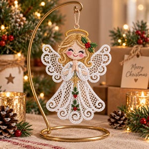 May include: A decorative angel ornament featuring intricate white lace wings and a matching lace dress with green holly and red berry accents. The angel has embroidered golden hair, a halo, and a smiling face, suspended from a curved gold metal stand.