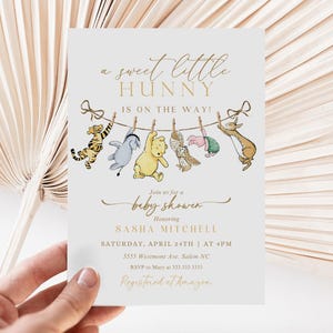 May include: A Winnie the Pooh themed baby shower invitation with a line of characters hanging on a clothesline. The text reads "a sweet little hunny is on the way!"  Join us for a baby shower honoring Sasha Mitchell. Saturday, April 24th at 4pm. 5555 Westmont Ave. Salem NC. RSVP to Mary at 333.333.3333. Registered at Amazon.