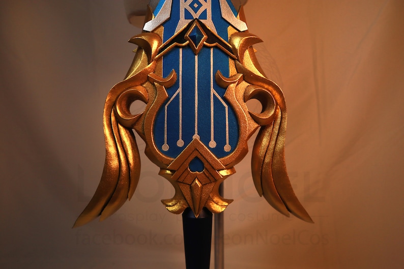 May include: A gold and blue decorative sword with intricate details. The sword has a blue blade with gold accents and a gold handle with a blue and gold design.