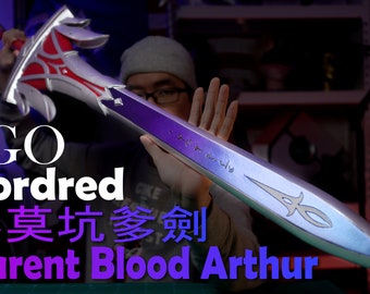 May include: A silver and purple sword with a red and silver hilt. The sword has intricate details and is inscribed with text in a foreign language. The text "FGO Mordred 小莫 騎士 劍 Clarent Blood Arthur" is visible in the image.