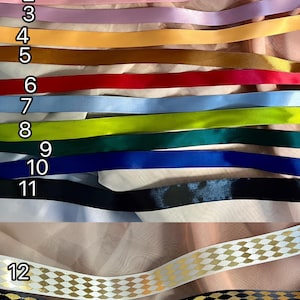 May include: A variety of ribbon styles are displayed, each with a unique color and design. The ribbons range from solid colors like cream, pink, and blue to patterned designs with gold accents. The text "Ribbon styles" is at the top.