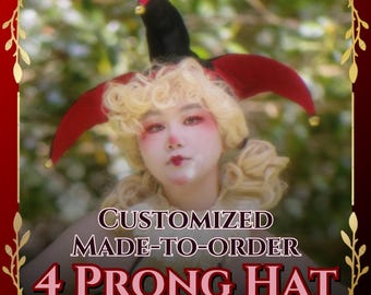 Può includere: Un cappello a quattro punte con sezioni in tessuto nero e rosso e piccoli campanellini dorati alle estremità. Il testo sull'immagine recita: CUSTOMIZED MADE-TO-ORDER 4 PRONG HAT. Il cappello è indossato sopra capelli biondi ricci e un colletto a balze.