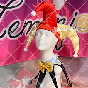 May include: A jester costume on a mannequin head. The costume includes a red and yellow jester hat with white pom-poms, a blue and white collar, a yellow bow tie, and black and white accents. The background has the text "Lemonjolly".