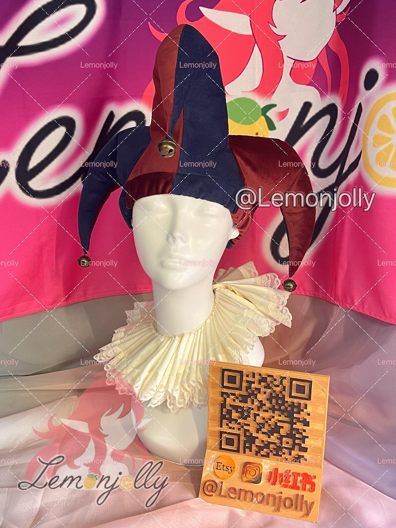 May include: A jester's hat with burgundy and navy blue panels, adorned with small bells. A white ruffled collar and a wooden sign with a QR code and social media handles are also visible. The background is pink and white.