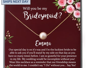 May include: A gold-filled necklace with a pearl pendant, presented on a burgundy card. The card features floral accents and the text "Will you be my Bridesmaid?" with a personalized name. A thoughtful gift for a wedding.