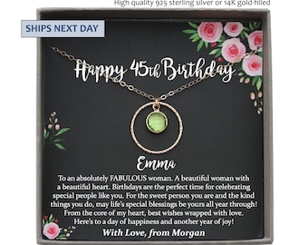 May include: A gold-colored necklace with a green gemstone pendant, presented in a gift box. The necklace is part of a birthday gift set, with the words "Happy 45th Birthday" and the name "Emma" displayed on the card.