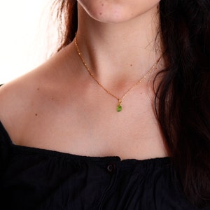 May include: A gold chain necklace with a small green gemstone pendant.