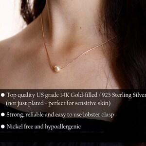 May include: A delicate gold necklace featuring a single, luminous pearl pendant. The necklace is suspended on a fine chain, creating a minimalist and elegant design. The pearl is a soft, creamy color, and the chain appears to be gold-filled.