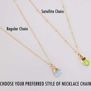 May include: Two gold necklaces with different chain styles: a regular chain and a satellite chain. Both necklaces have a small gemstone pendant attached.