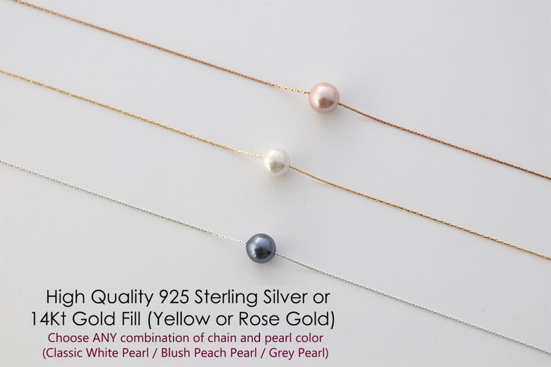 May include: Three delicate necklaces with a single pearl pendant each. The pearls are white, blush peach, and grey. The chains are silver and gold.