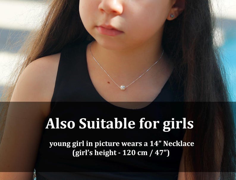 May include: A silver necklace with a single, round pearl pendant. The necklace is worn by a person wearing a black top. The text on the image says "Also Suitable for girls" and mentions a 14-inch necklace.