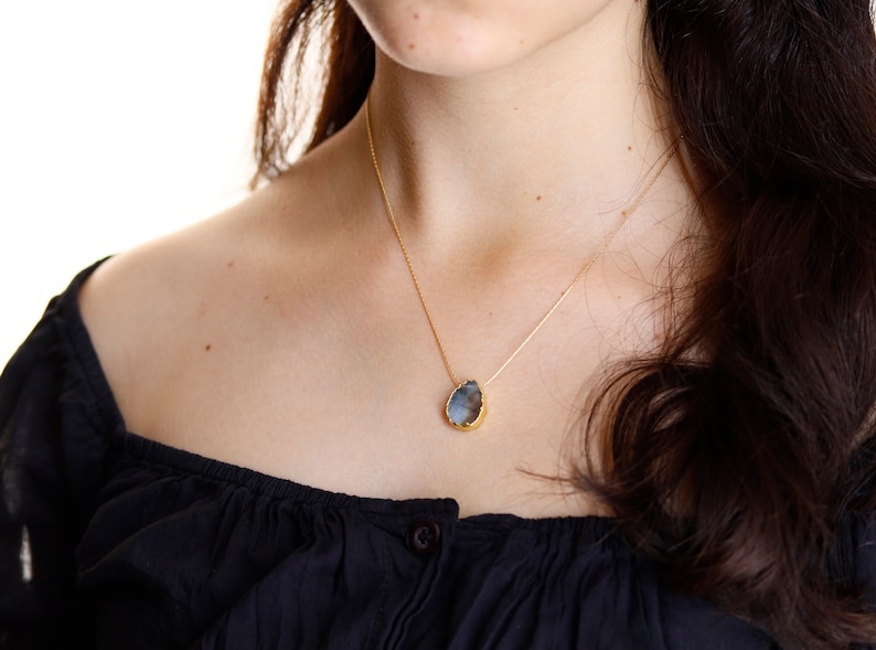 May include: A gold chain necklace with a teardrop-shaped pendant featuring a grey stone.