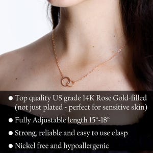 Puede incluir: Un collar de oro rosa de 14 quilates con dos anillos circulares entrelazados en una cadena fina. El texto en la imagen dice: Top quality US grade 14K Rose Gold-filled, Fully Adjustable length 15-18, Strong, reliable and easy to use clasp, Nickel free and hypoallergenic.