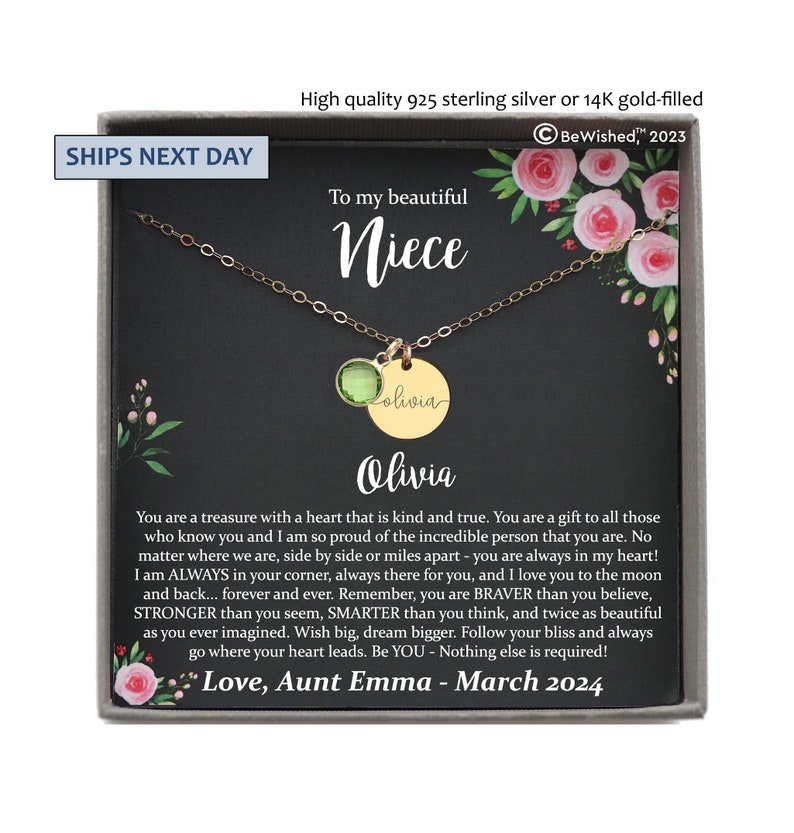 May include: A gold-toned necklace featuring a round green gemstone charm and a circular pendant engraved with the name Olivia. The necklace is presented in a gift box with a card featuring floral illustrations and a printed message addressed to a niece.