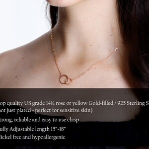 May include: A rose gold-colored necklace featuring two interlocking circular rings as a pendant on a delicate chain. The text states: Top quality US grade 14K rose or yellow Gold-filled / 925 Sterling Silver, strong, reliable and easy to use clasp, fully adjustable length 15-18 inches, nickel free and hypoallergenic.