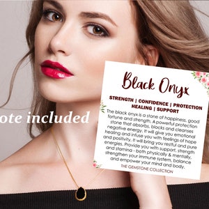 K&ouml;nnte beinhalten: Ein tropfenf&ouml;rmiger schwarzer Onyx-Anh&auml;nger an einer d&uuml;nnen Goldkette. Eine quadratische wei&szlig;e Karte ist enthalten mit dem Text Black Onyx, Strength, Confidence, Protection, Healing, Support und einem Text &uuml;ber die Steineigenschaften.