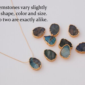 May include: A gold chain necklace with a large, iridescent, teardrop-shaped gemstone pendant. The pendant is surrounded by a gold rim. The image also shows several other similar gemstones, all with different shapes and colours.
