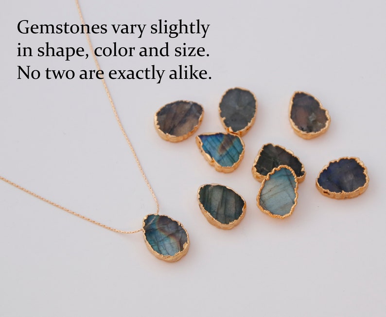 May include: A gold chain necklace with a large, iridescent, teardrop-shaped gemstone pendant. The pendant is surrounded by a gold rim. The image also shows several other similar gemstones, all with different shapes and colours.