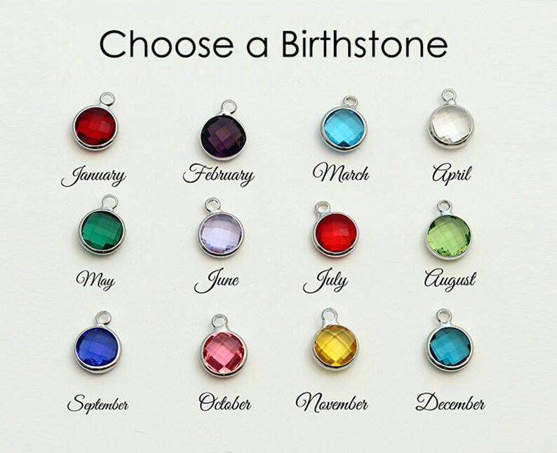 Puede incluir: Un gr&aacute;fico titulado Choose a Birthstone que muestra doce dijes circulares de tono plateado, cada uno con una piedra preciosa facetada de diferente color para los meses de enero a diciembre, etiquetados con texto en cursiva negra debajo.