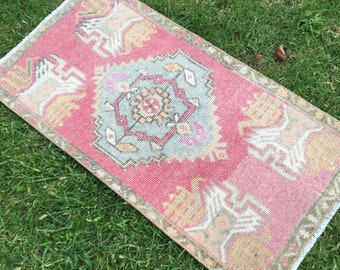 May include: A pink and blue patterned rug with a fringed edge. The rug has a traditional design with geometric shapes and floral motifs.