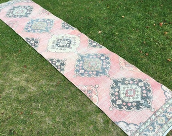 May include: A pink and black patterned runner rug with a floral design. The rug is laid out on a green grassy lawn.