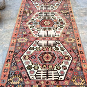 May include: A traditional Turkish rug with a geometric pattern in shades of red, blue, green, and white. The rug features a central medallion with a repeating hexagonal design.
