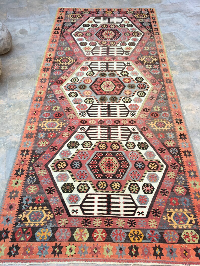 May include: A traditional Turkish rug with a geometric pattern in shades of red, blue, green, and white. The rug features a central medallion with a repeating hexagonal design.