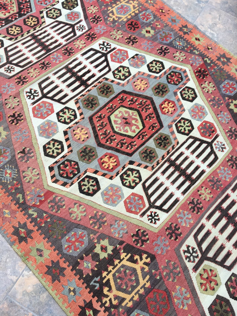 May include: A colorful rug with a geometric pattern in shades of red, blue, green, and brown. The rug has a traditional design with intricate details.