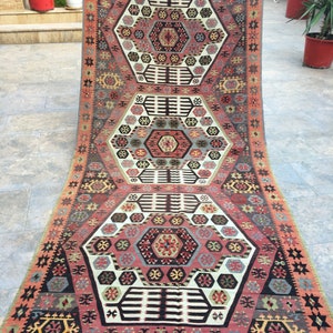 May include: A traditional Turkish rug with a geometric pattern in shades of red, blue, and white. The rug has a central medallion and a border with repeating motifs.