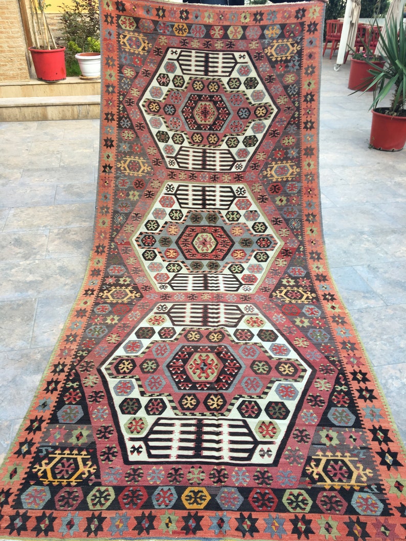 May include: A traditional Turkish rug with a geometric pattern in shades of red, blue, and white. The rug has a central medallion and a border with repeating motifs.