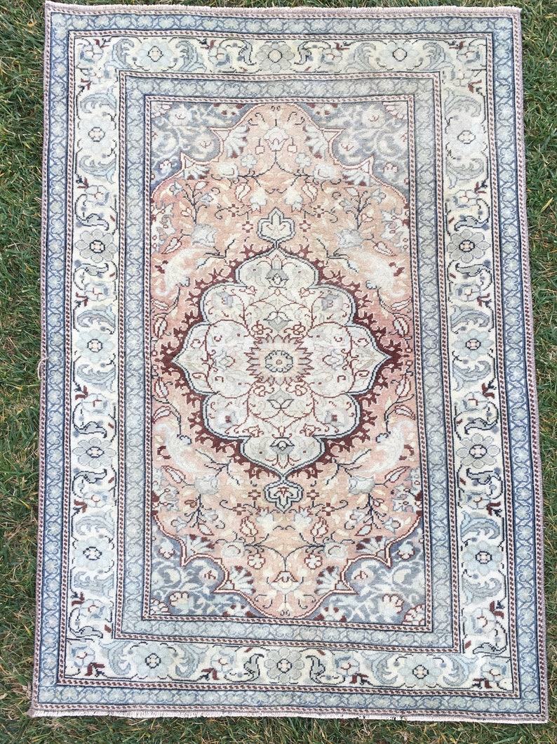 Peut inclure: Un tapis vintage avec un motif floral rose p&acirc;le et brun. Le tapis a une bordure bleu clair avec un motif floral.