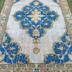 May include: A large, rectangular rug with an ornate, traditional design. The rug features a central medallion and corner elements in shades of blue, gold, and cream. The border is a mix of gold and blue, with a cream-colored fringe.