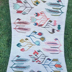 May include: A white rug with a repeating pattern of stylized floral designs in shades of red, blue, green, and pink.
